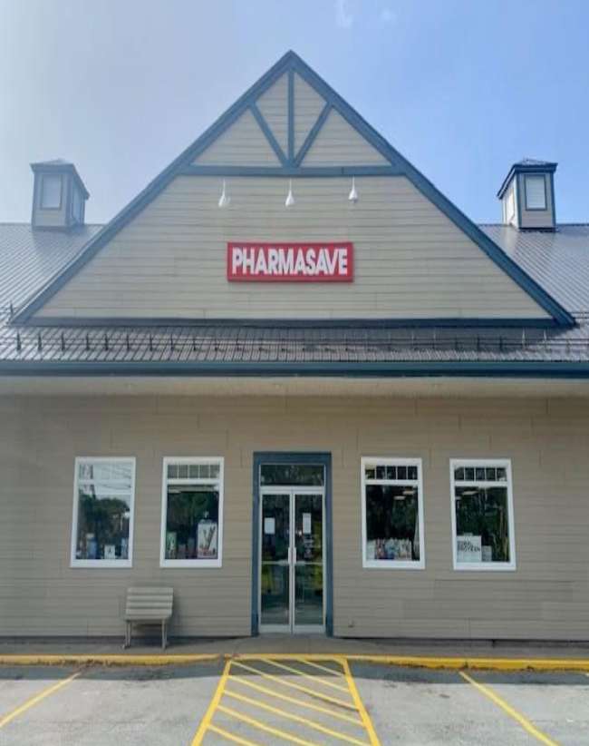 White exterior of a Pharmasave store with 4 empty parking spots out front.