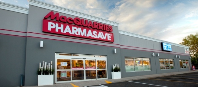 White and grey building with Wilson's Pharmasave signage out front and multiple empty parking spots