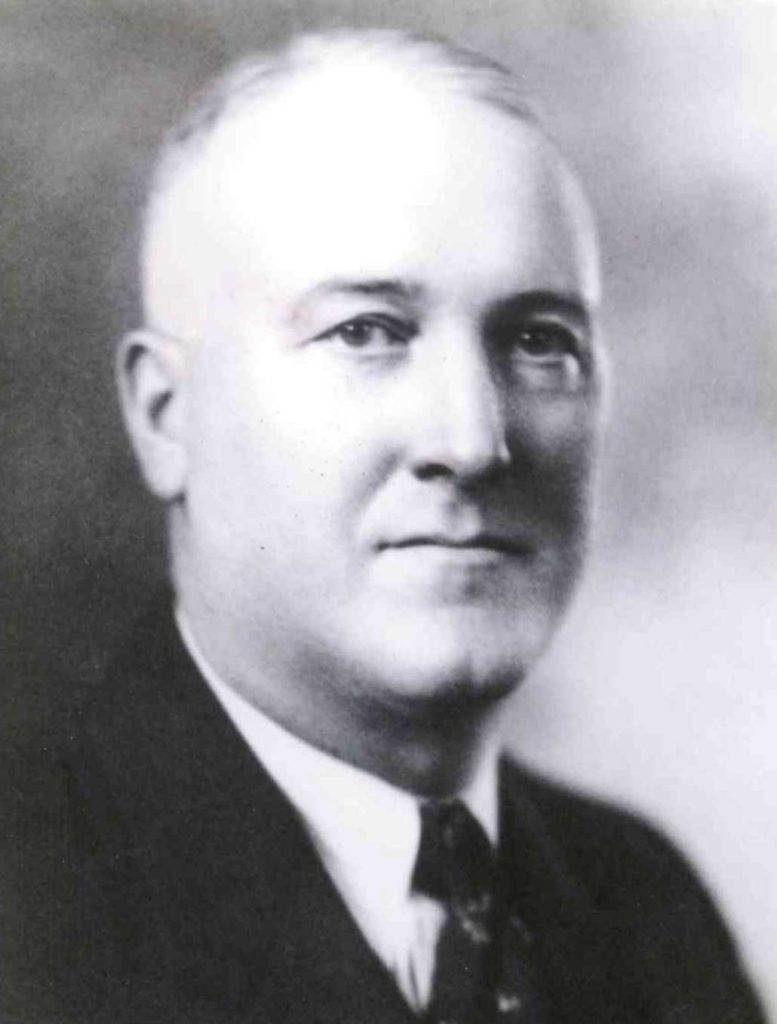 Black-and-white photo of a middle-aged man wearing a shirt and tie