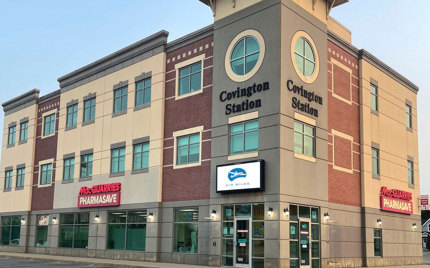 Covington Station building featuring MacQuarries Pharmasave storefront with modern brick and beige architecture, multiple stories, and street-level retail space.